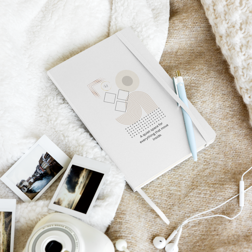 White ardcover notebook with minimalist geometric design styled with a pen, photos and earphones