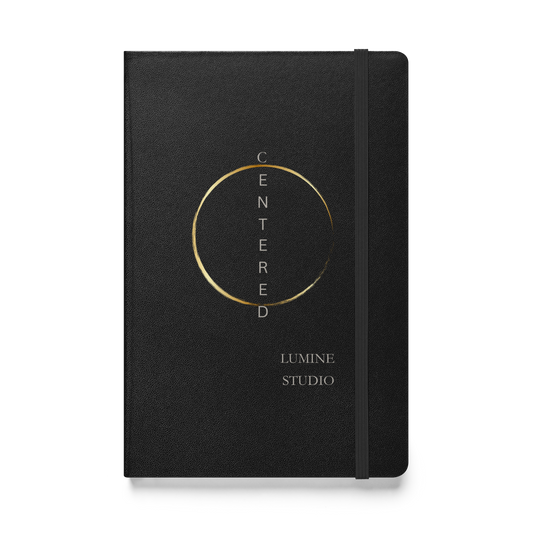 Black hardcover notebook with a minimalist gold circle design and elastic band, front view