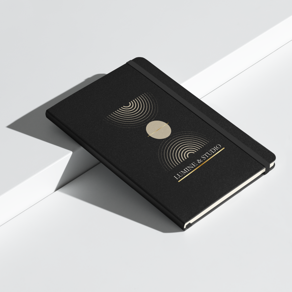 Black Lumine Studio hardcover notebook shown at an angle with minimalist gold geometric design