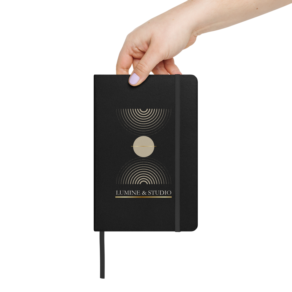 Hand holdong the black Lumine Studio hardcover notebook with minimalist gold geometric design