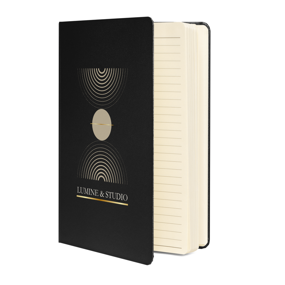 Black Lumine Studio hardcover notebook shown from the side with cream lined pages and minimalist gold geometric design