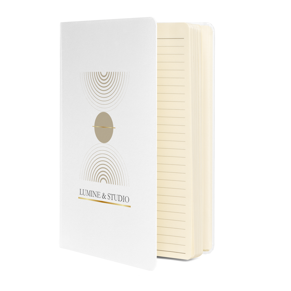 White Lumine Studio hardcover notebook sown partially open with cream lined pages and minimalist gold geometric design